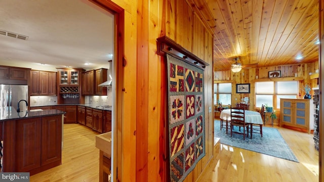 kitchen featuring visible vents, wooden ceiling, light wood-style flooring, appliances with stainless steel finishes, and wood walls