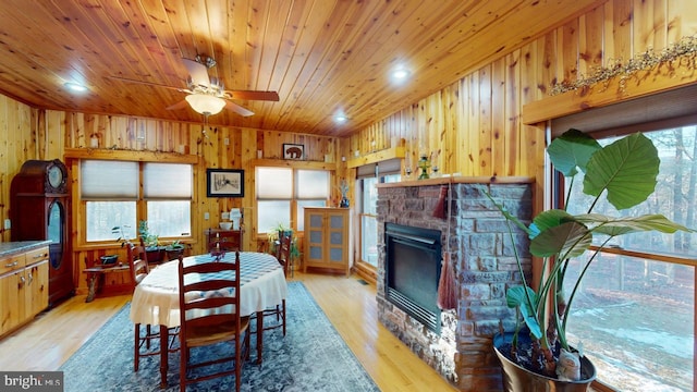 dining room featuring wooden ceiling, wooden walls, and light wood-style floors