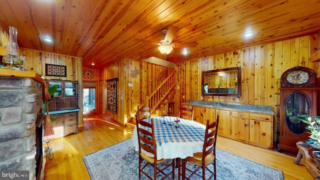 dining area with wood ceiling, wooden walls, light wood finished floors, and stairs