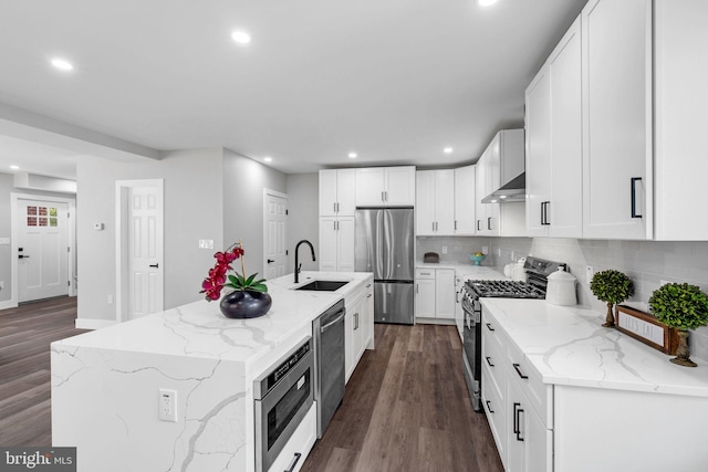 kitchen with sink, white cabinetry, stainless steel appliances, dark wood-type flooring, and a center island with sink