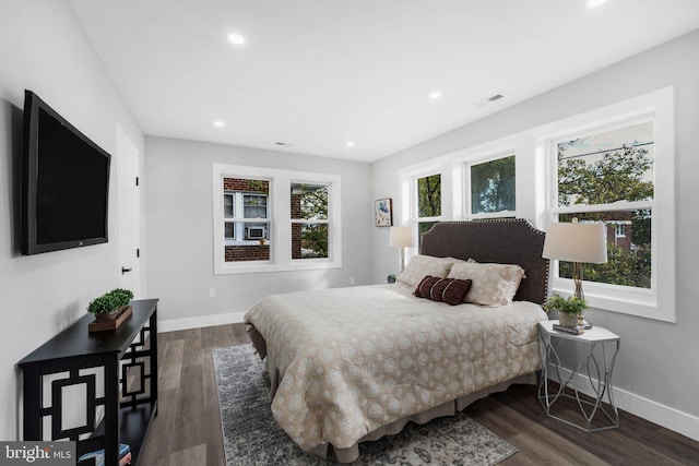 bedroom with multiple windows and dark hardwood / wood-style flooring