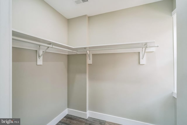 walk in closet with dark wood-type flooring