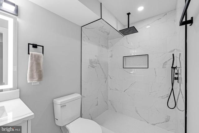 bathroom with vanity, toilet, and tiled shower