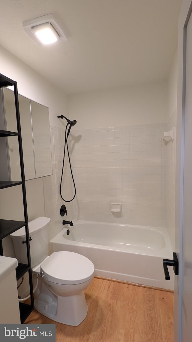 bathroom featuring toilet, tiled shower / bath combo, and hardwood / wood-style flooring