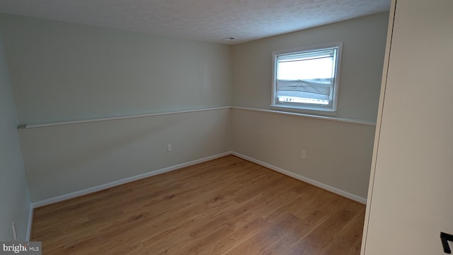 spare room featuring light wood-type flooring and a textured ceiling