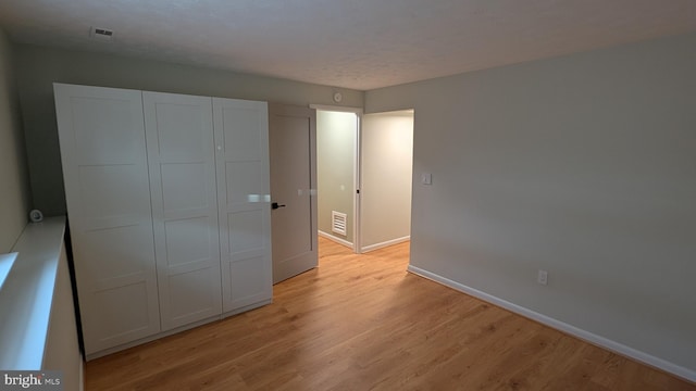 unfurnished bedroom featuring light hardwood / wood-style floors and a closet