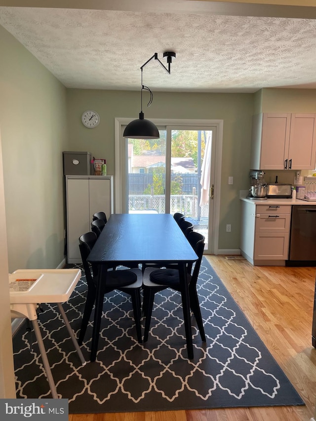 dining area featuring a textured ceiling and light hardwood / wood-style floors