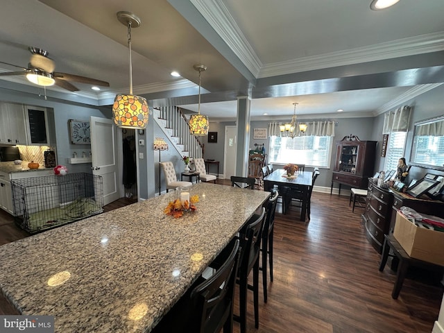 kitchen featuring ornamental molding, light stone countertops, decorative light fixtures, ceiling fan with notable chandelier, and dark hardwood / wood-style flooring