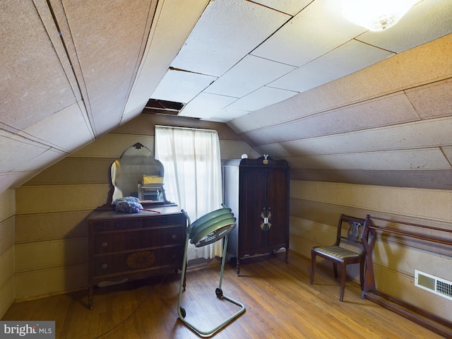 office space with lofted ceiling, hardwood / wood-style floors, and wood walls