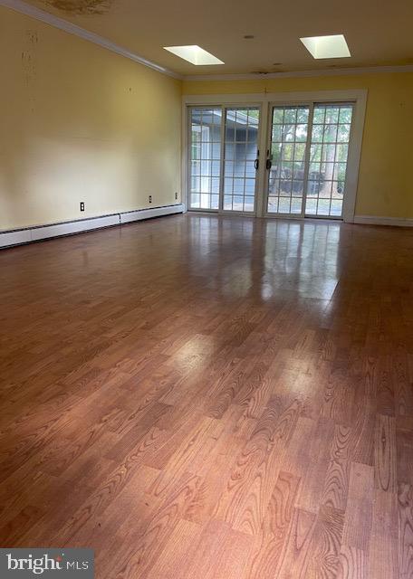 spare room featuring hardwood / wood-style floors, a skylight, and crown molding