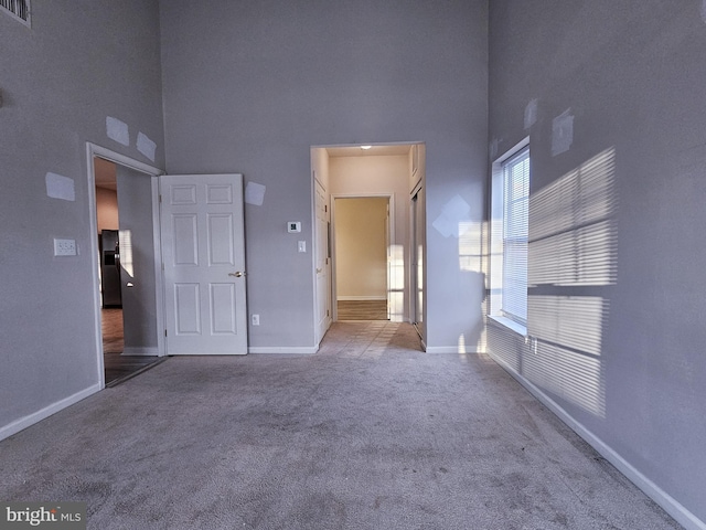 empty room with carpet and a towering ceiling