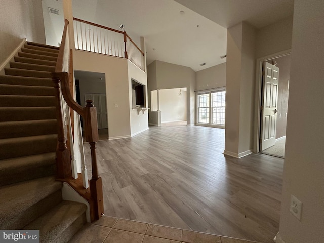 unfurnished living room with light hardwood / wood-style floors and a towering ceiling