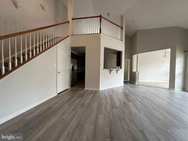 unfurnished living room with hardwood / wood-style floors and a high ceiling