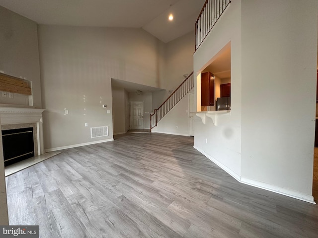 unfurnished living room featuring light wood-type flooring and high vaulted ceiling