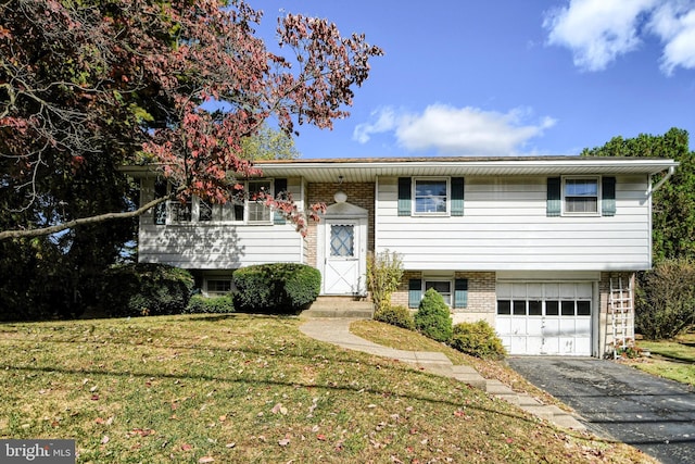 bi-level home with a front yard, an attached garage, and aphalt driveway