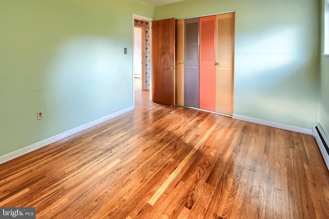 unfurnished bedroom featuring wood finished floors, a closet, and baseboards