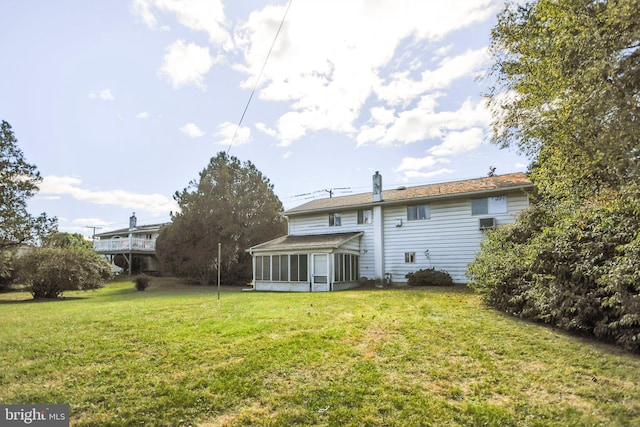 rear view of property featuring a yard and a sunroom