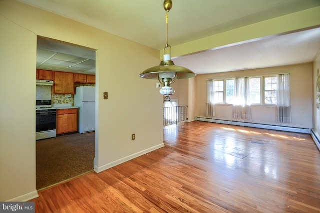 unfurnished dining area featuring a baseboard radiator, baseboards, and wood finished floors