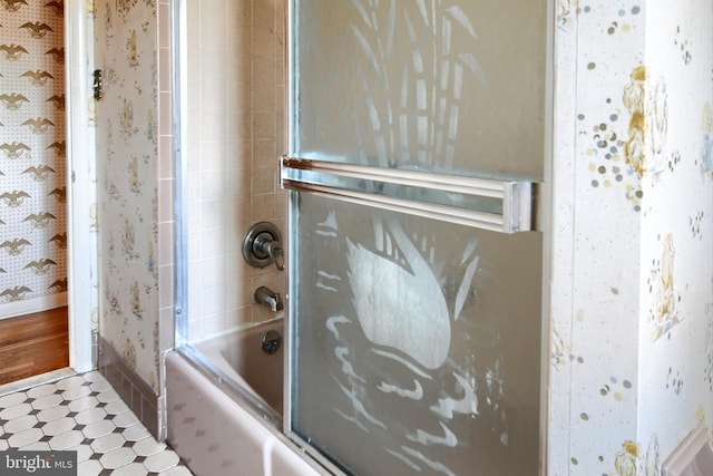 bathroom with tile patterned floors, baseboards, wallpapered walls, and bath / shower combo with glass door
