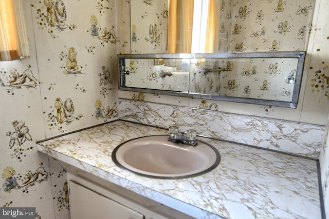 bathroom with decorative backsplash, vanity, and wallpapered walls