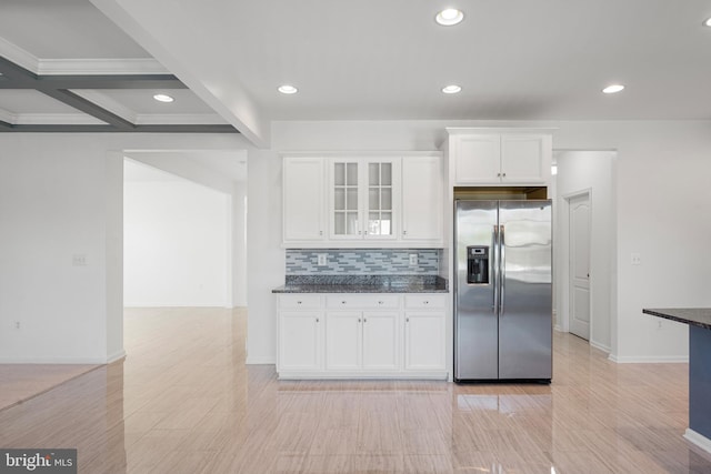 kitchen with stainless steel fridge, backsplash, white cabinetry, dark stone counters, and beamed ceiling