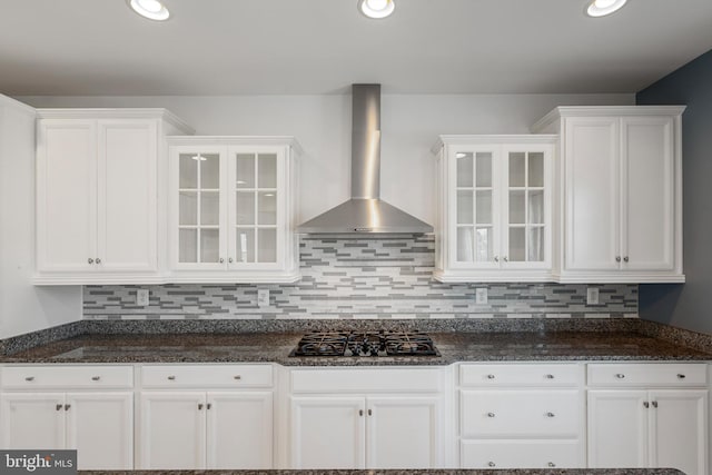 kitchen with wall chimney exhaust hood, decorative backsplash, white cabinetry, and black gas cooktop