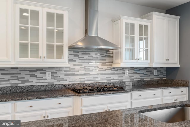 kitchen featuring white cabinetry, wall chimney exhaust hood, dark stone counters, and black gas cooktop