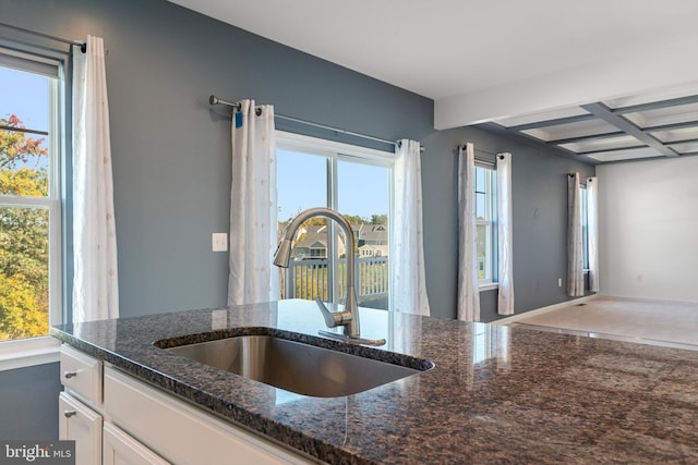 kitchen featuring sink, white cabinetry, coffered ceiling, beamed ceiling, and dark stone counters