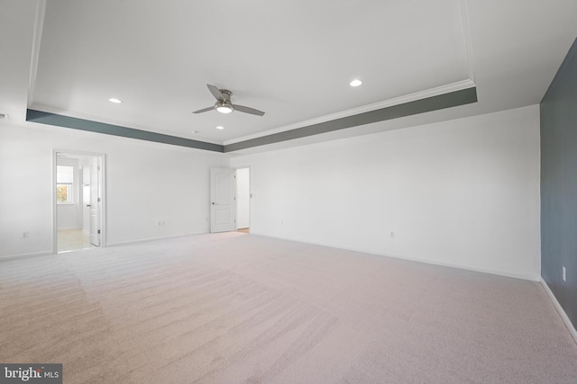 spare room featuring ornamental molding, light carpet, a tray ceiling, and ceiling fan