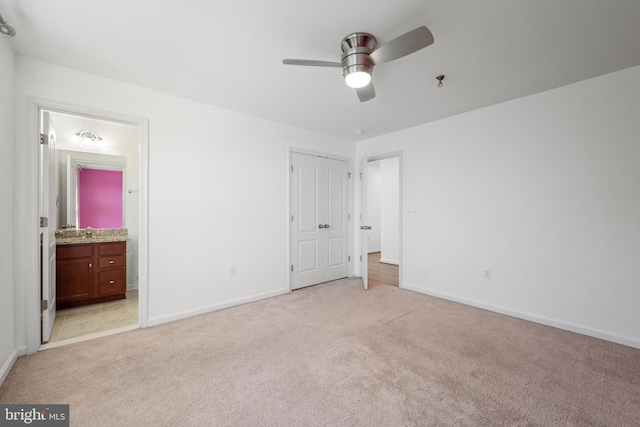 unfurnished bedroom featuring sink, light carpet, ensuite bathroom, and ceiling fan