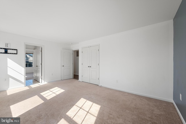 unfurnished bedroom featuring light colored carpet and a closet