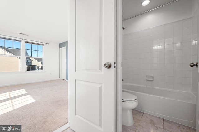 bathroom with toilet, tiled shower / bath, and tile patterned flooring