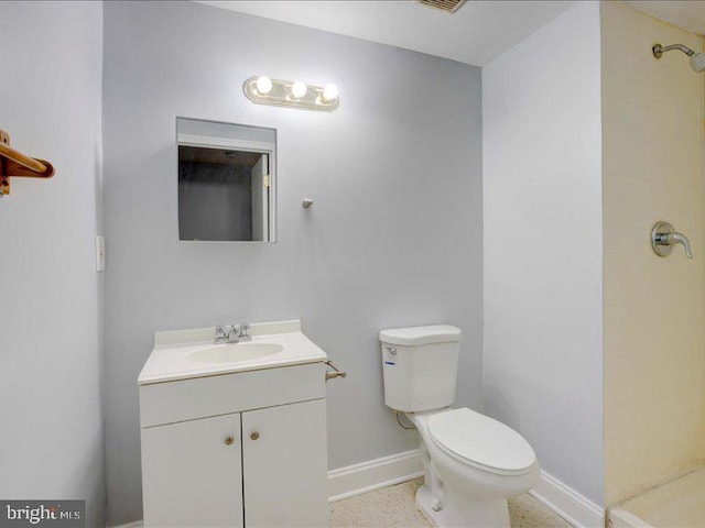 bathroom with a tile shower, toilet, and vanity