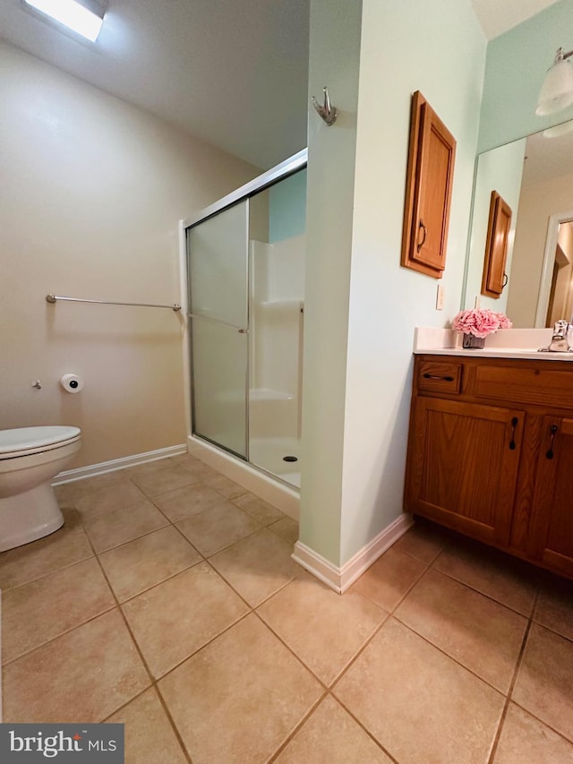 bathroom featuring tile patterned floors, toilet, a shower with door, and vanity