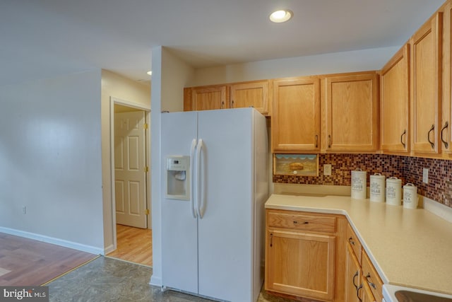 kitchen with tasteful backsplash, white refrigerator with ice dispenser, light brown cabinets, and light hardwood / wood-style flooring