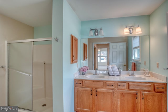 bathroom featuring a shower with door and vanity