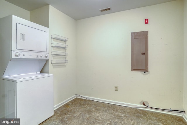 clothes washing area featuring electric panel and stacked washing maching and dryer