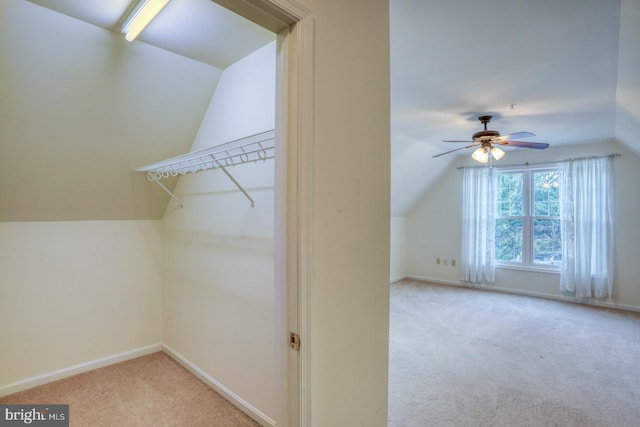 walk in closet featuring light colored carpet, vaulted ceiling, and ceiling fan