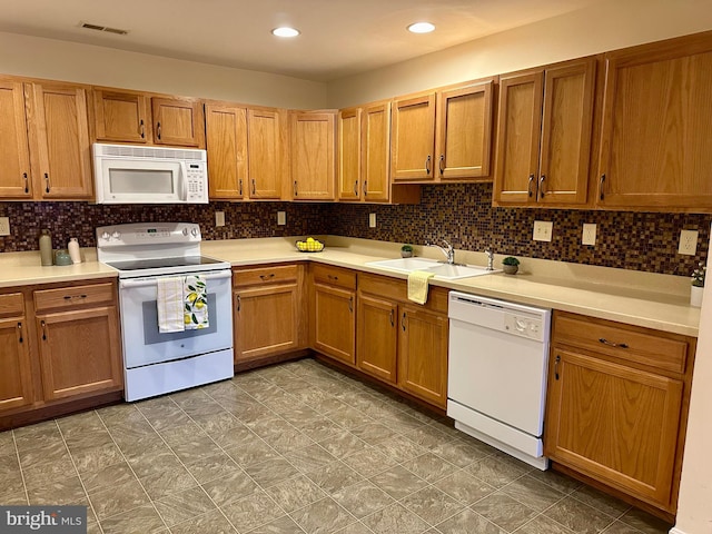 kitchen featuring white appliances, sink, and backsplash