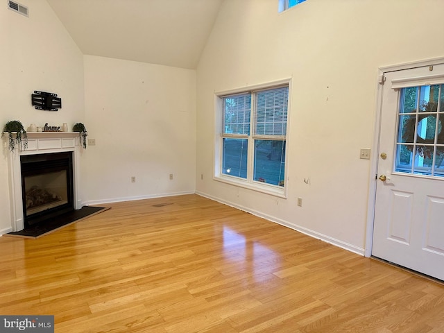 unfurnished living room featuring light hardwood / wood-style flooring, plenty of natural light, and high vaulted ceiling