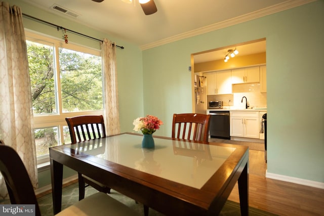 dining area with wood-type flooring, crown molding, sink, and ceiling fan