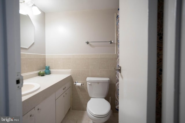 bathroom with tile walls, tile patterned floors, vanity, and toilet