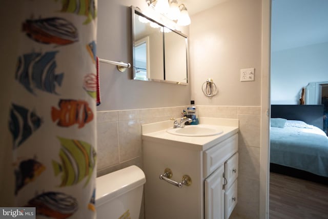 bathroom featuring hardwood / wood-style flooring, vanity, tile walls, and toilet