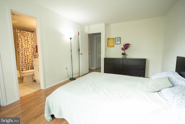 bedroom with connected bathroom and light hardwood / wood-style flooring