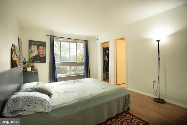 bedroom featuring a spacious closet, a closet, and hardwood / wood-style floors