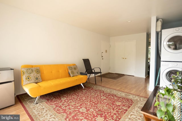 living area featuring hardwood / wood-style flooring and stacked washer / dryer