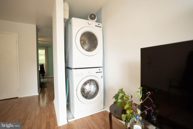 laundry room with stacked washer and dryer and hardwood / wood-style flooring