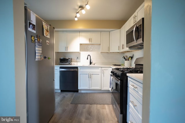 kitchen featuring decorative backsplash, sink, dark hardwood / wood-style flooring, white cabinetry, and appliances with stainless steel finishes