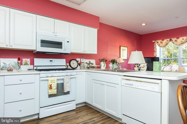 kitchen featuring white appliances, dark hardwood / wood-style flooring, sink, kitchen peninsula, and white cabinets