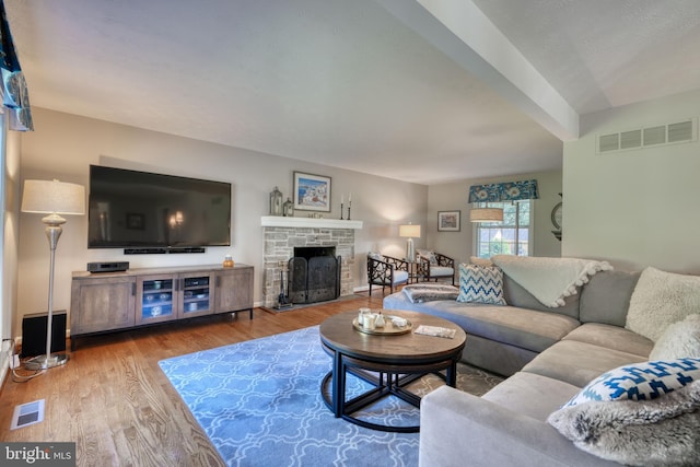 living room with a fireplace, beamed ceiling, and hardwood / wood-style flooring